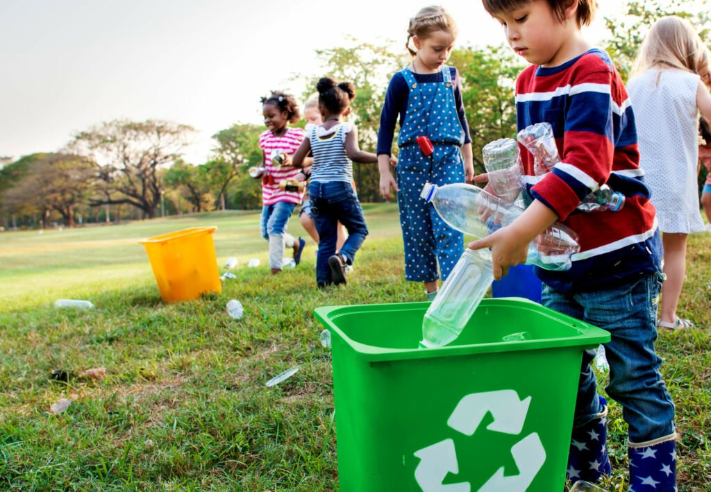 Kid recycling a plastic bottle in the green recycle bin